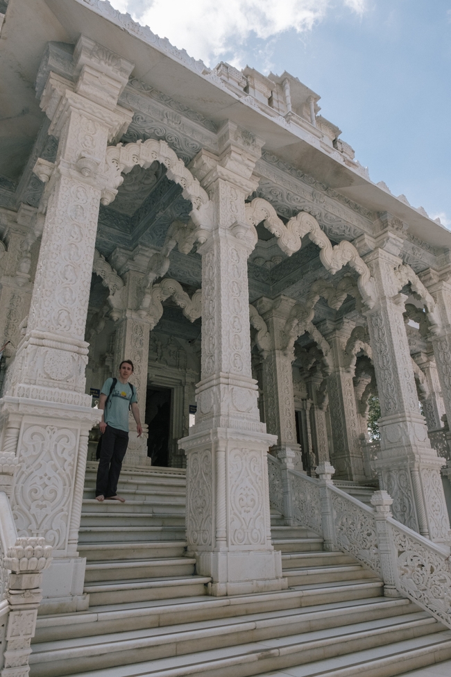 Alex stands on the ornate steps of a beautifully carved white marble Jain temple, looking relaxed and happy.